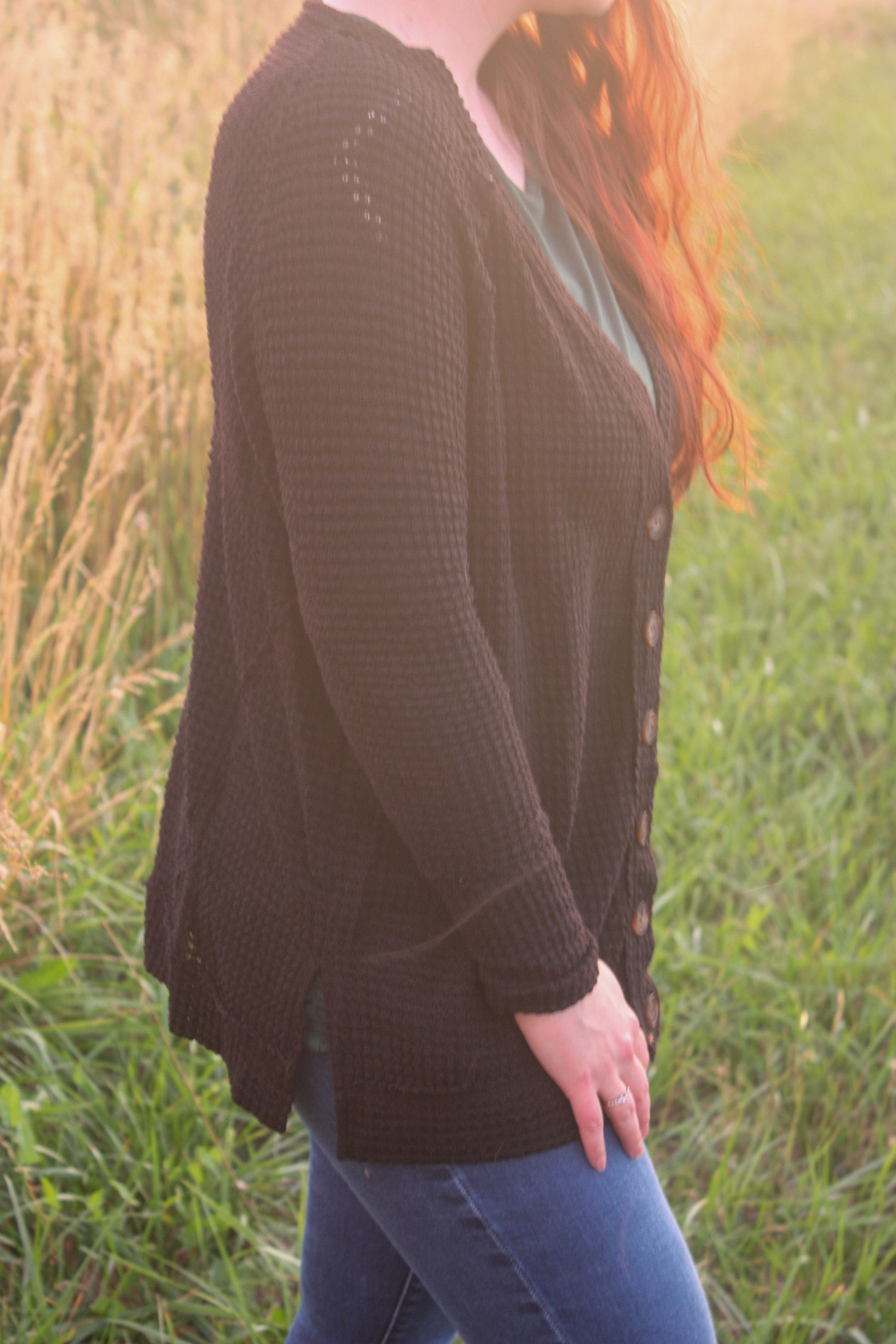 Person wearing a black cardigan in a grassy field