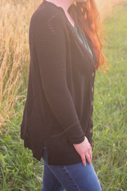Person wearing a black cardigan in a grassy field