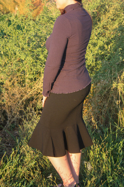 Person wearing a navy ribbed long sleeve top and black midi skirt with a ruffle mermaid style bottom standing in a grassy outdoor setting