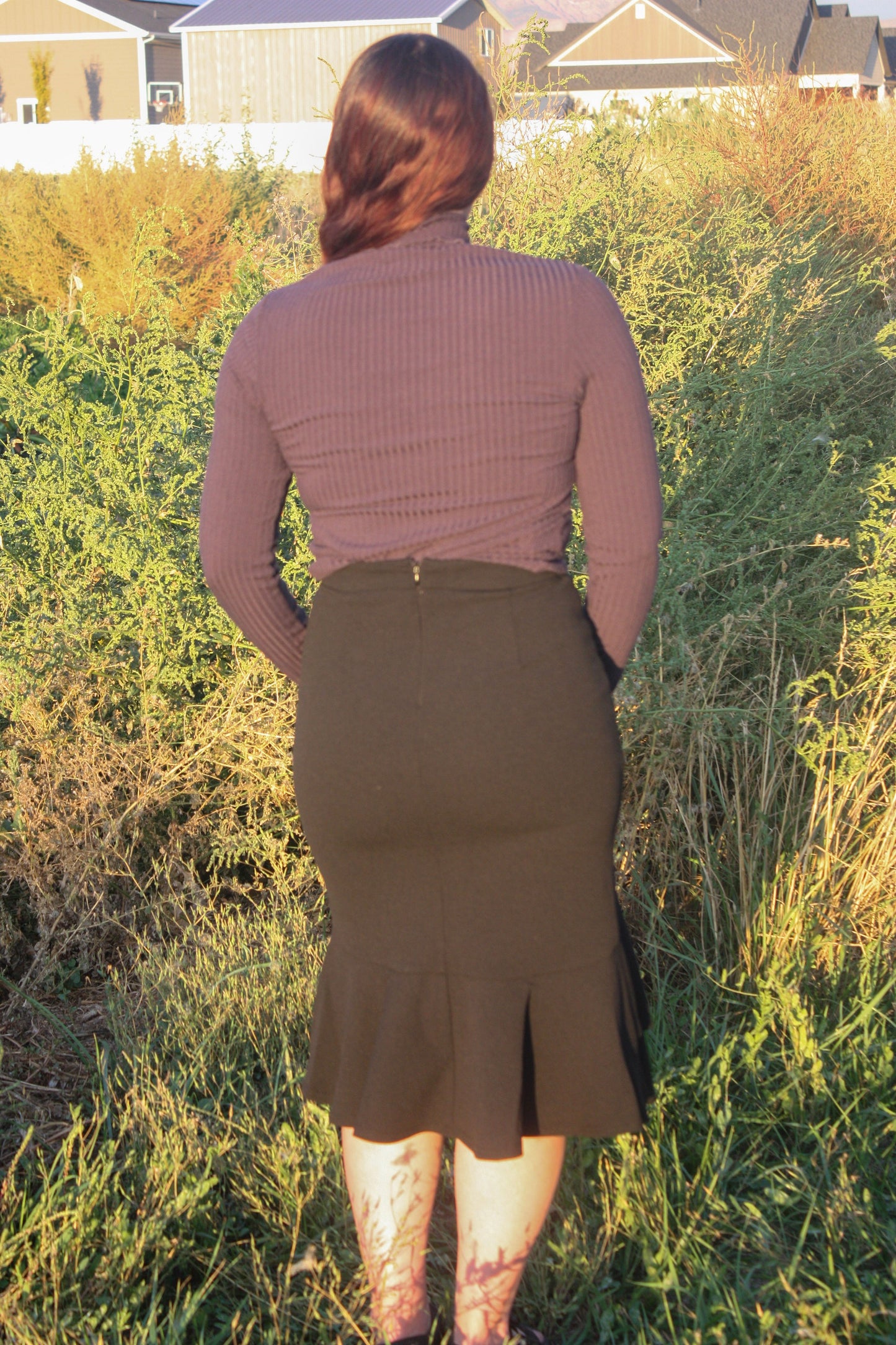 Person wearing a navy ribbed long sleeve top and black midi skirt with a ruffle mermaid style bottom standing in a grassy outdoor setting